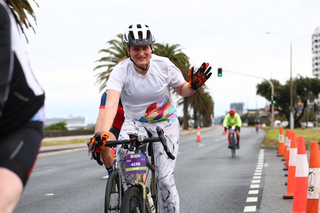 Riding along beach road, waving at camera