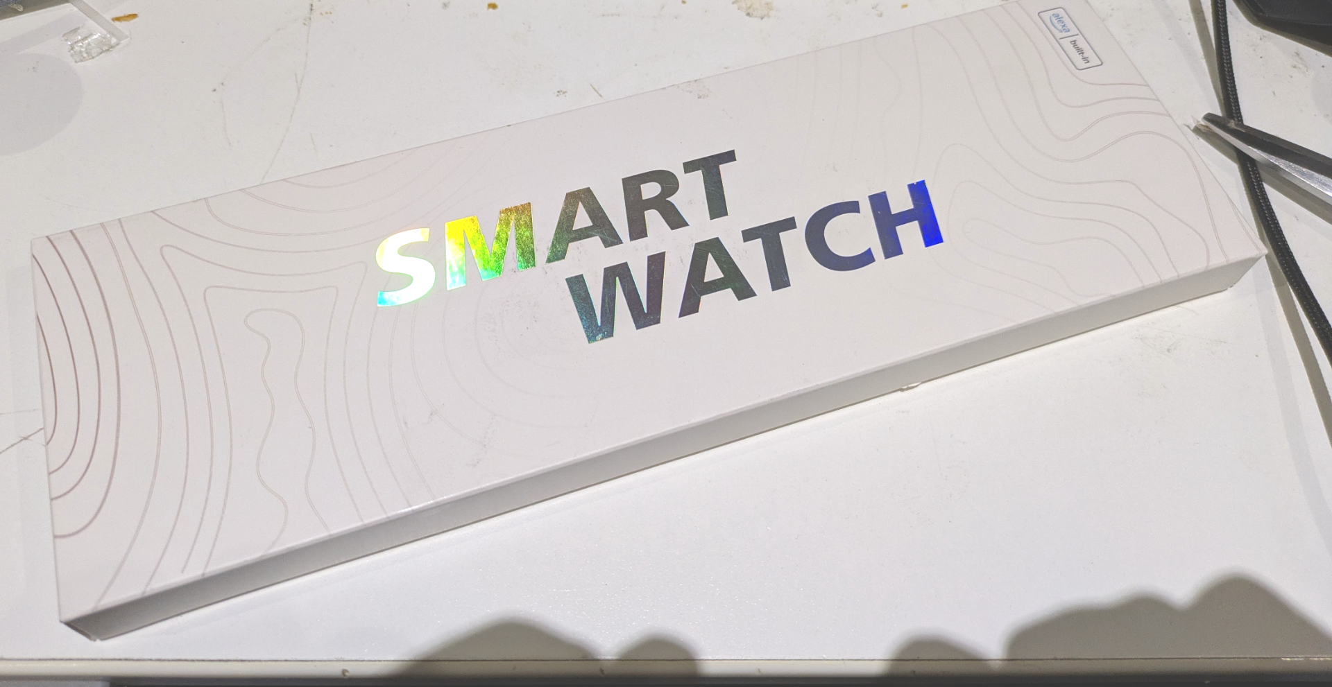 Box with shiny logo that says Smart Watch on my desk