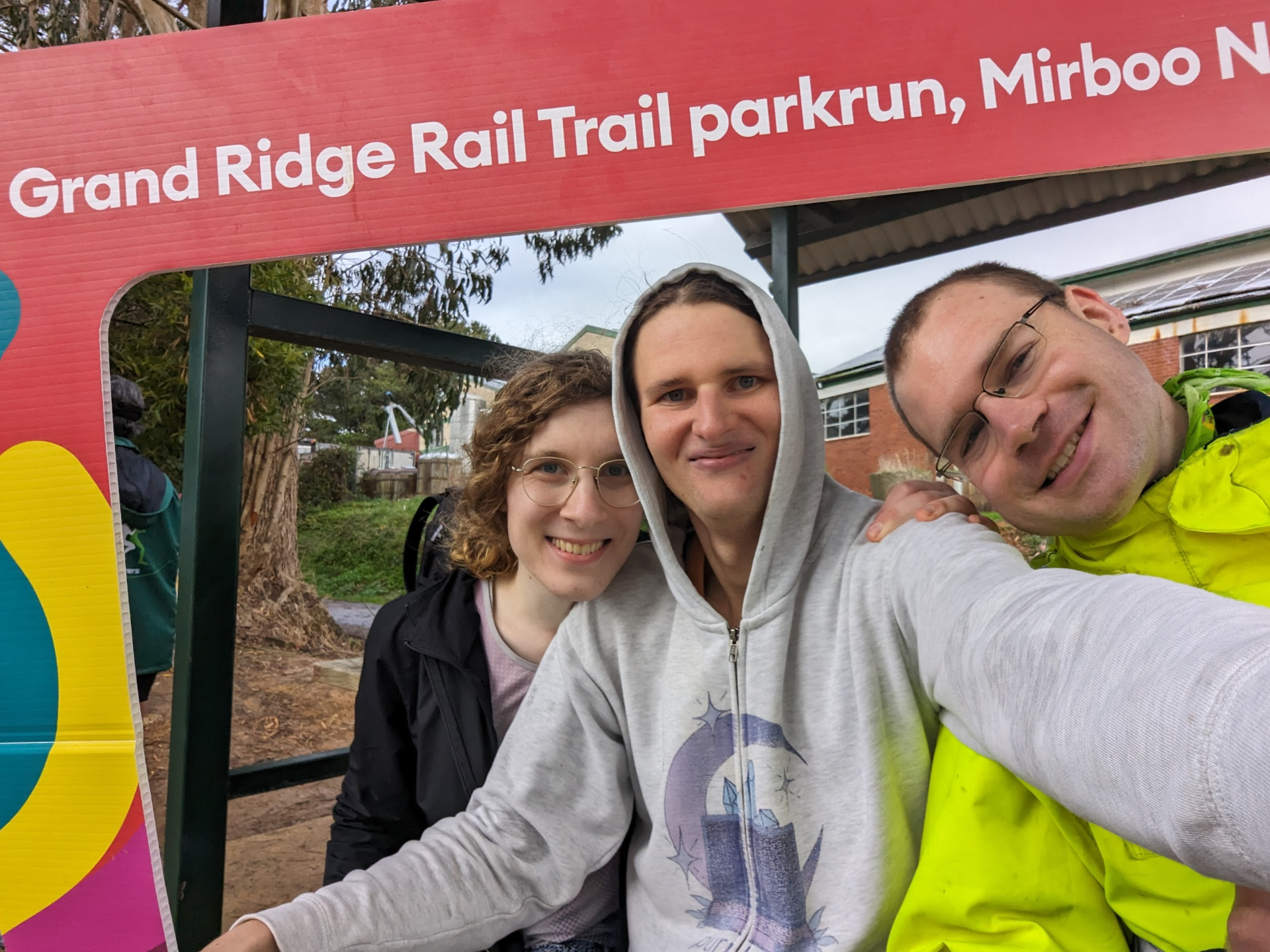 Selfie with Luke and Alex while holding up the Grand Ridge Rail Trail parkrun selfie border cardboard