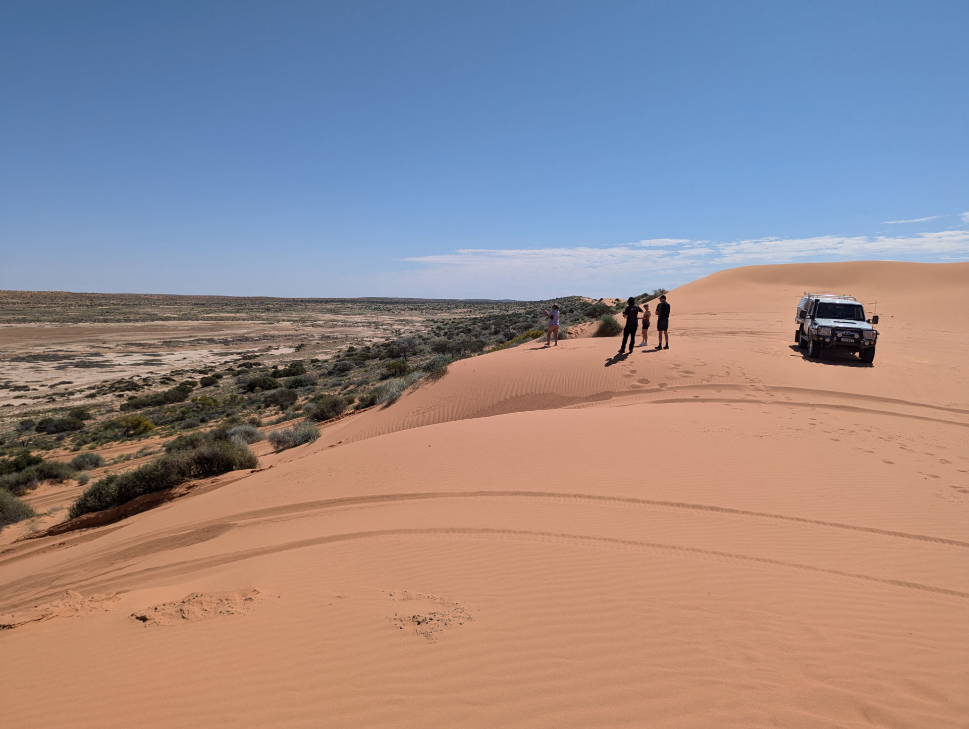 the top of big red covered in just sand. the top is flat and a 4x4 is sitting on top with people standing around talking