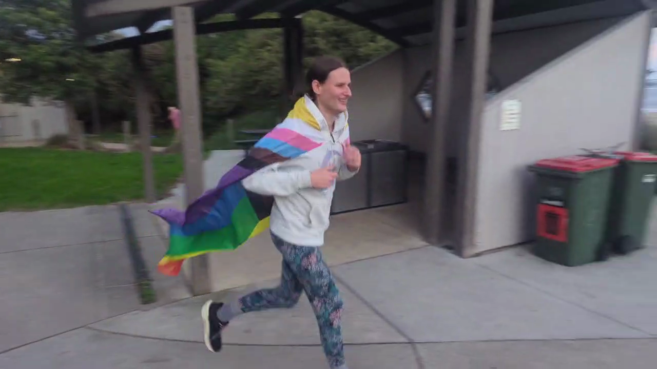 Me running in Inverloch with a progress pride flag worn as cape